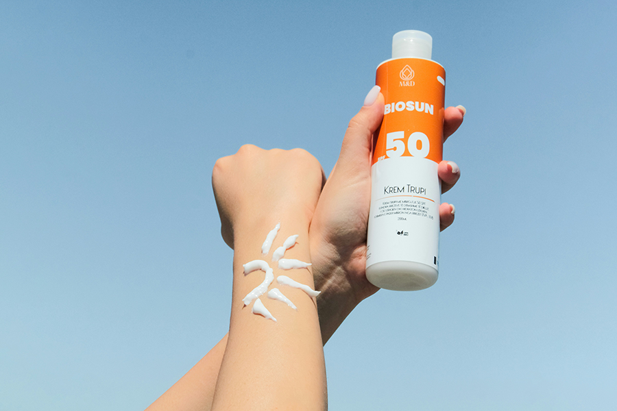 Hands holding a bottle of SPF 50 sunscreen