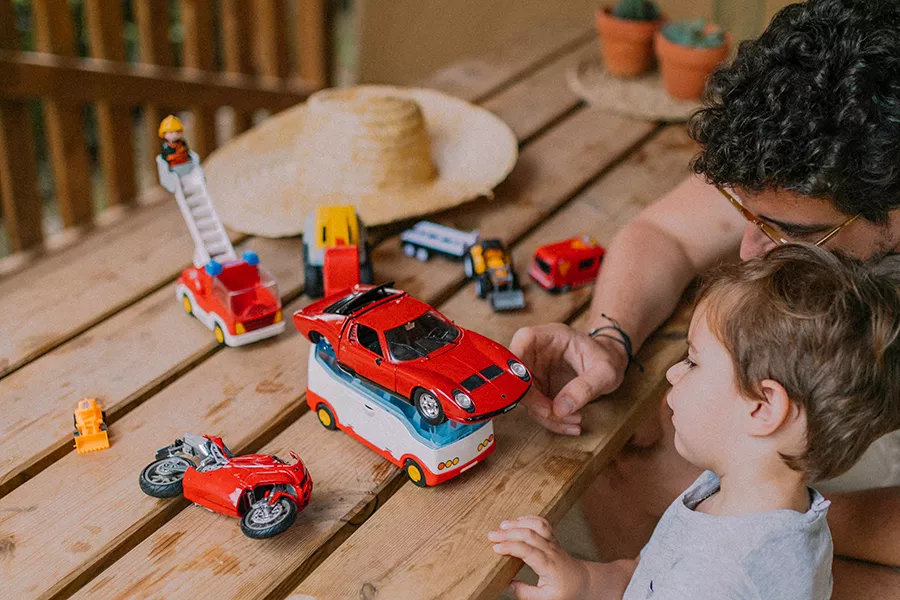 Father and his son playing with toy cars and vehicles