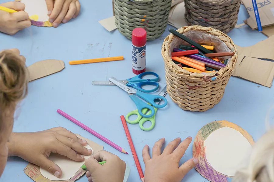 Kids coing some crafts on a table with crayons, glue and scissors