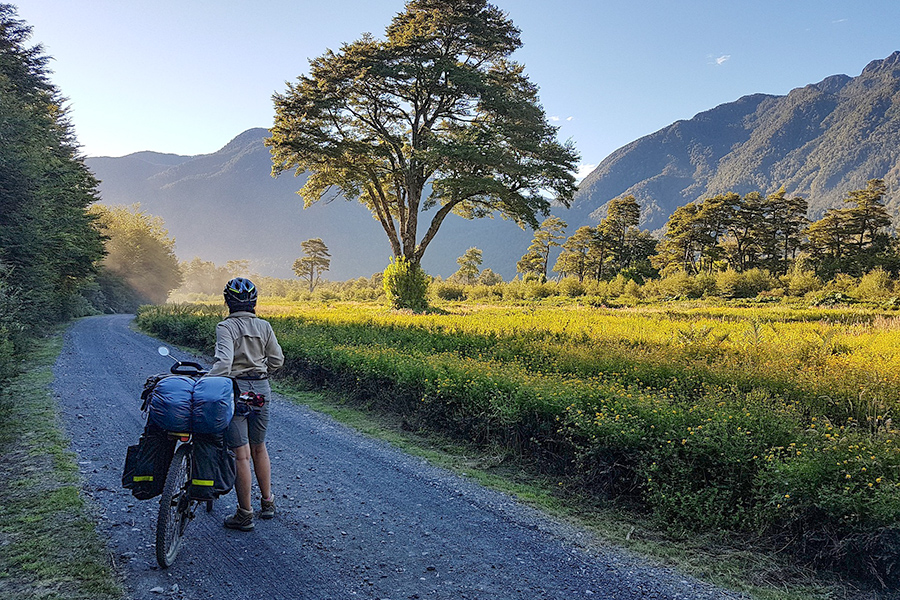 Cyclist beside his bike on a dirt track.