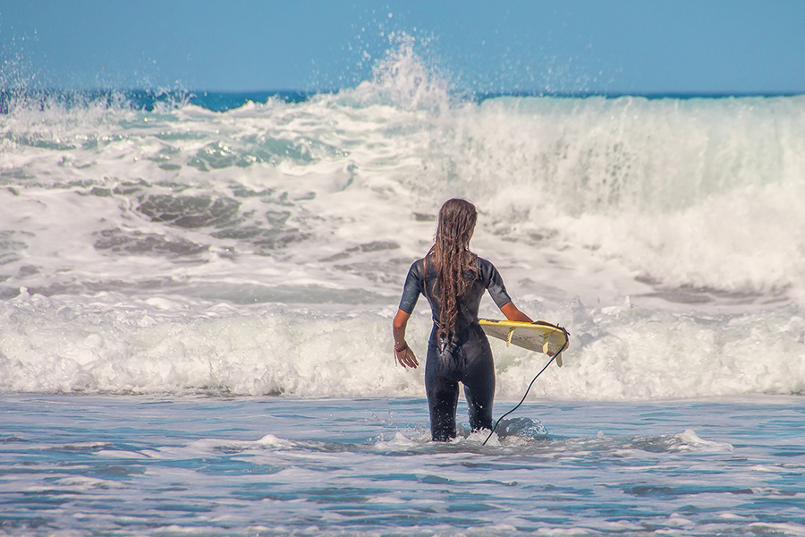 A woman in a wetsuit holding a surfboard in the sea.