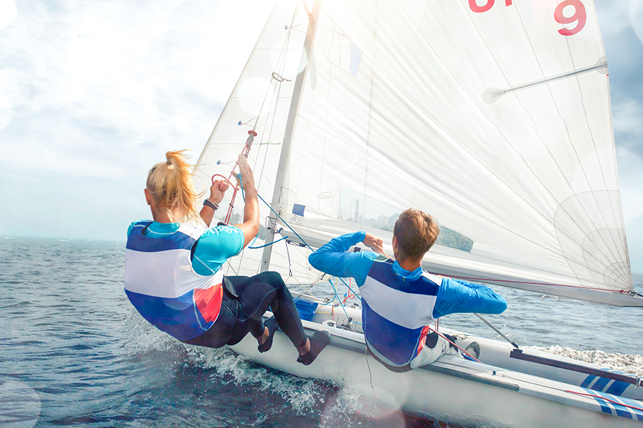 Two people enjoying a sailboat ride on a sunny day.