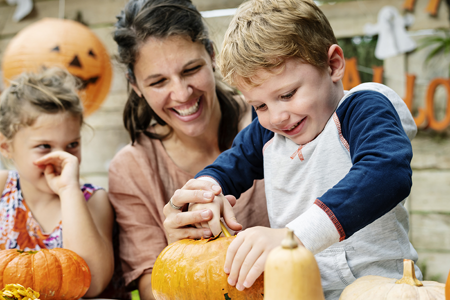 Bambino che intaglia una zucca per Halloween con sua madre e sua sorella