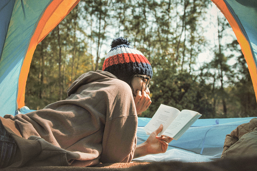 someone reading a book in their tent in the forest