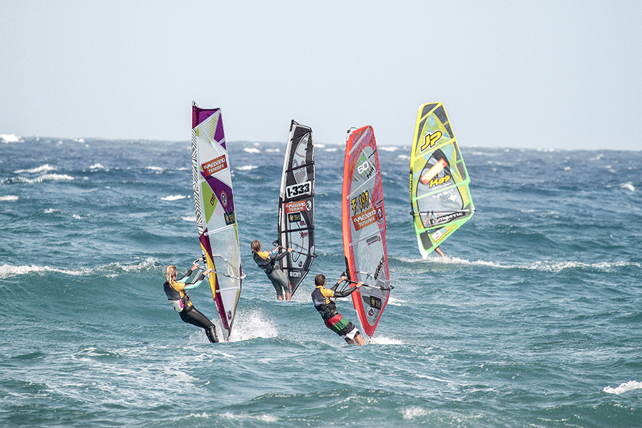 Four people windsurfing in the sea.